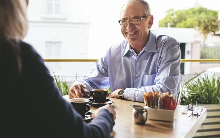 Smiling older man having coffee with a woman at coffee shop
