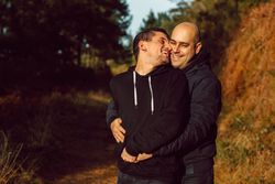 Smiling men hugging on path in park