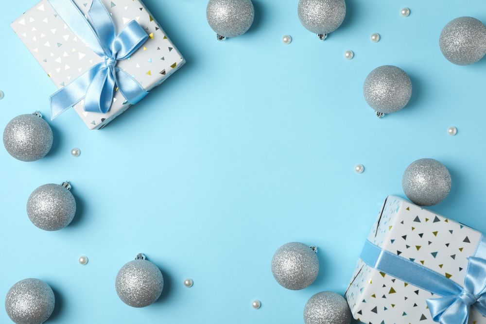 Christmas balls and presents on blue background, space for text