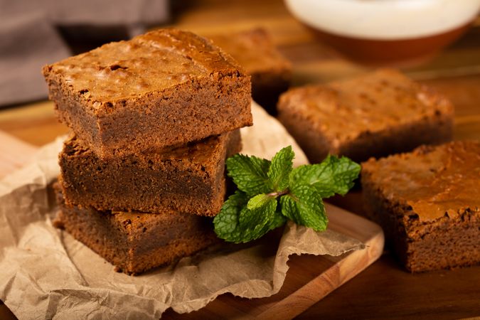 Chocolate brownies with fresh mint leaves served on wooden board