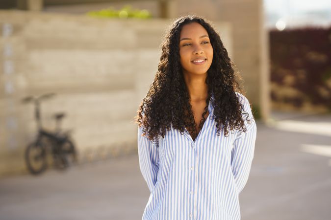 A Beautiful and Smiling Woman Wearing a Casual Striped Shirt While Enjoying the Outdoors