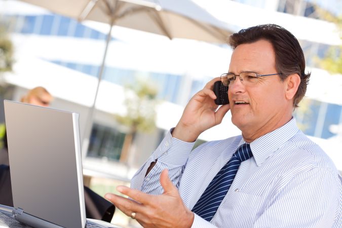 Businessman Talking on Cell Phone Using Laptop