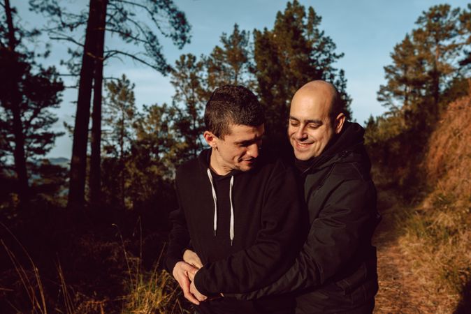 Smiling men hugging on path in park
