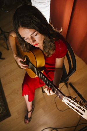 Woman singing and playing guitar on stage in lamplight