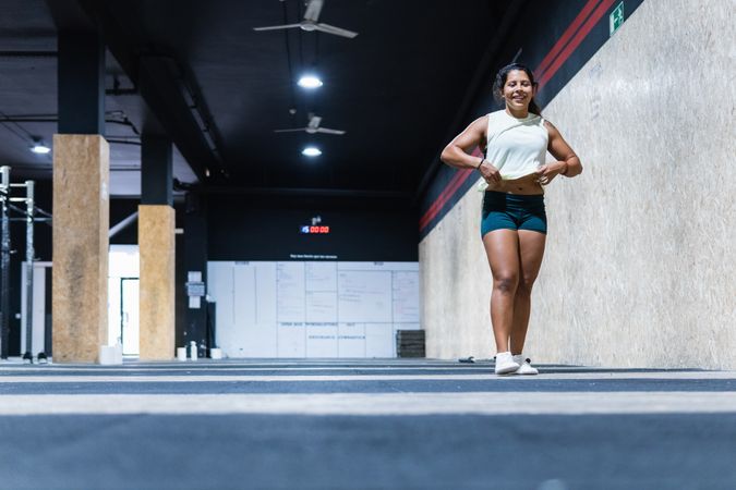 Positive Hispanic sportswoman walking in gym