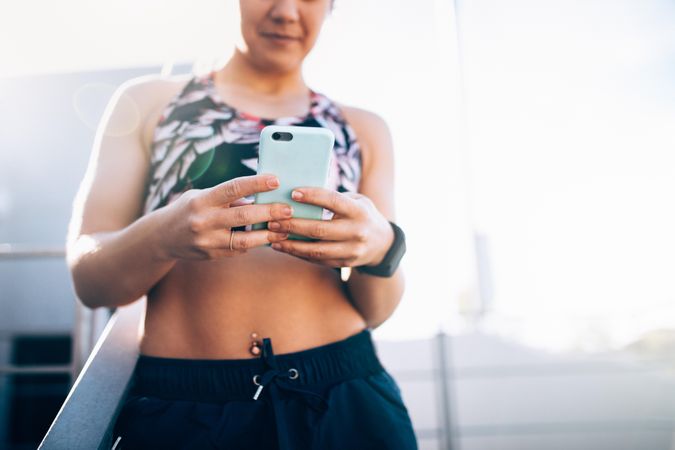 Young woman in sports bra checking mobile phone