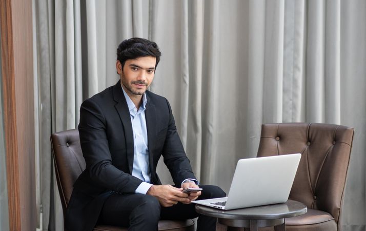 Businessman in suit with laptop sitting in leather seat