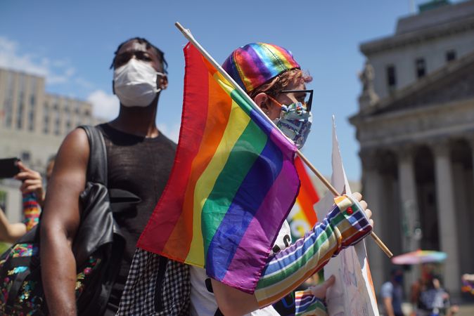 Man with facemask and woman holding rainbow flag at Queer Liberation March in New York City