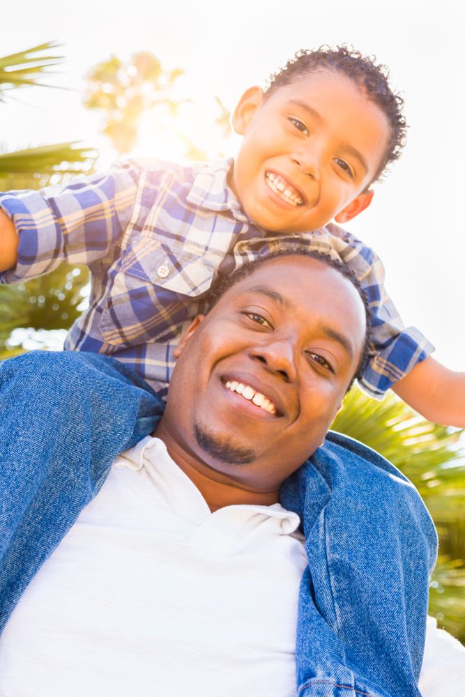 Son Piggybacking On Happy Father's Back Outdoors Together On Sunny Day