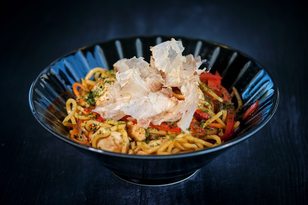 Appetizing noodles in bowl with crisps placed on table