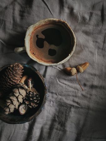 Dark coffee in ceramic mug on bed