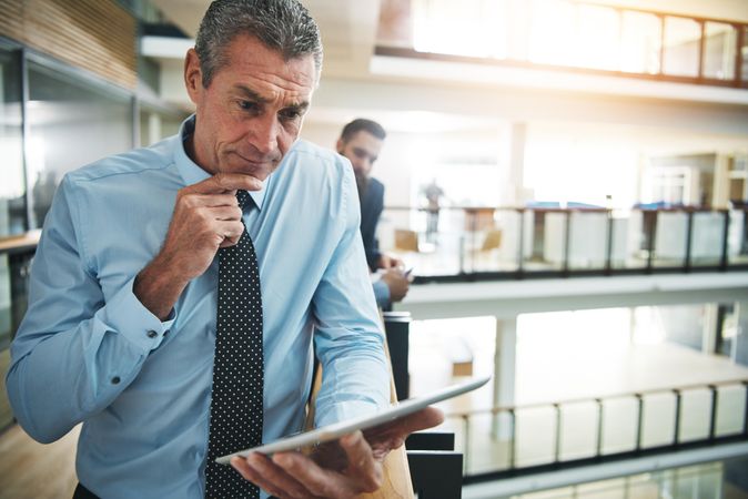 Portrait of pensive businessman smiling with tablet