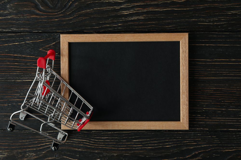 Shop cart and chalkboard on wooden background