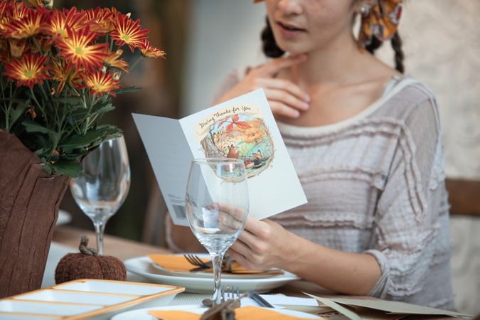 Cropped image of woman sitting in a restaurant reading food menu