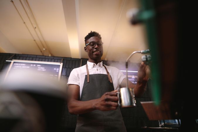 Low angle shot of man working in his coffee shop wearing an apron