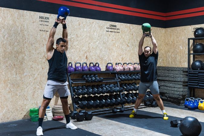 Hispanic sportspeople lifting kettlebells in gym