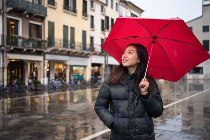 Asian female tourist with umbrella walking at city street on rainy weather