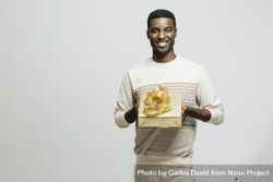 Smiling Black man presenting a gift wrapped in gold paper 5ok2Q5