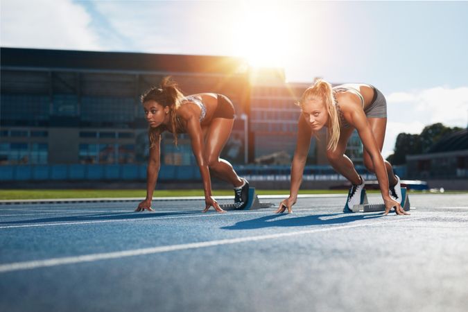 Two female athletes at starting position ready to start a race on track