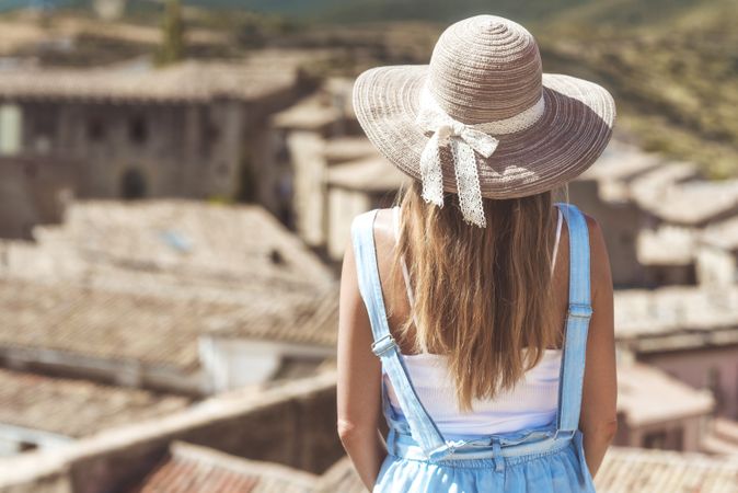 Woman in hat resting on street with scenic view