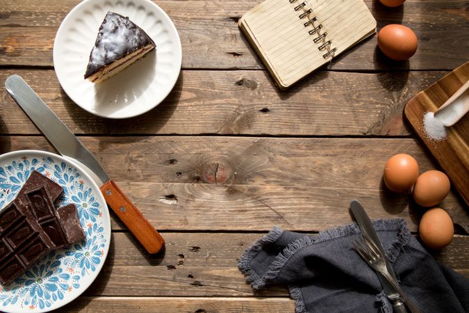 Eggs chocolate slice of cake and notebook on table