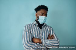 Portrait of a concerned Black man in face mask blue striped shirt with his arms crossed 0vgx75
