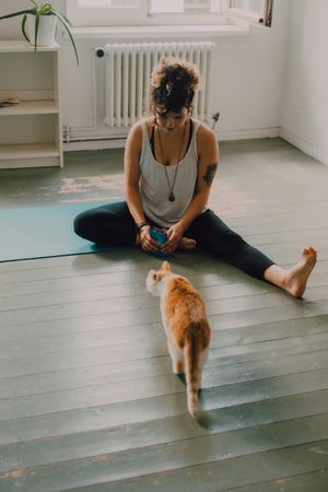 Relaxed woman playing with cat on floor at home