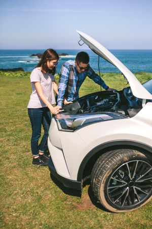 Young couple tries to fix the broken down car