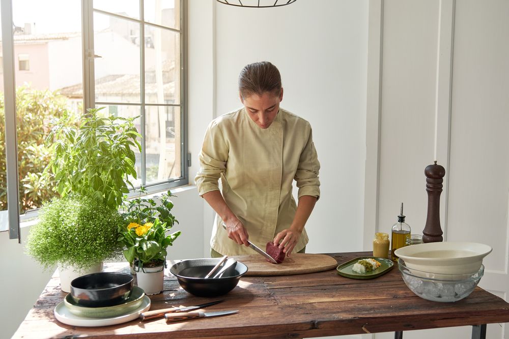 Serious woman cutting meat at home