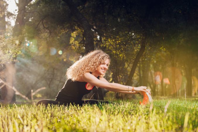 Happy woman stretching on sunny meadow