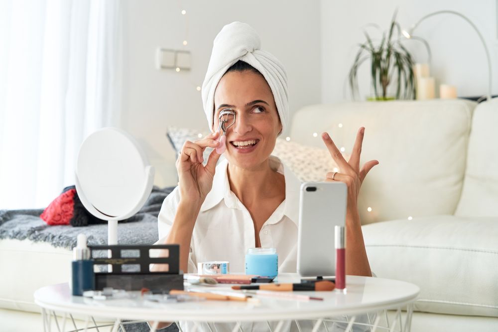 Happy woman applying eyelash curler