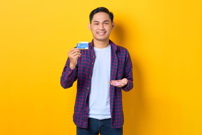 Man with credit card and cash in yellow studio shoot