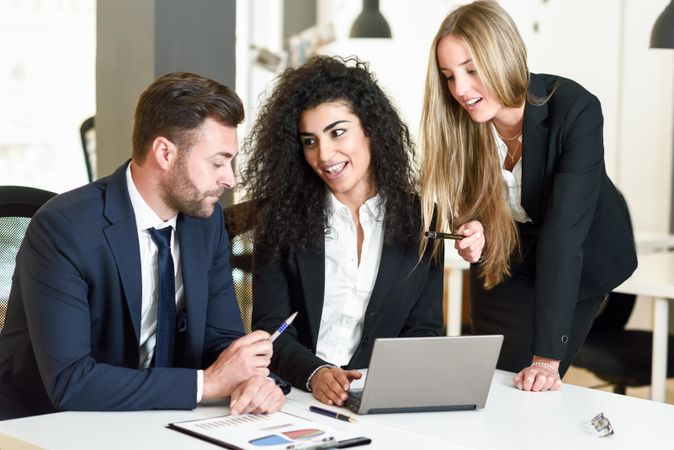 Business co-workers planning a project together in office around a laptop