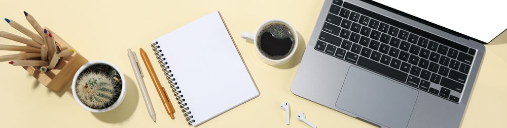 Top view banner of laptop, notebook, pens, coffee, cactus, earbuds with copy space