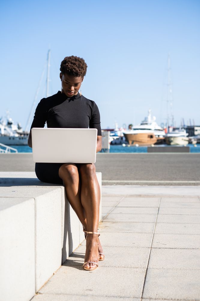 Serious female surfing laptop near modern building