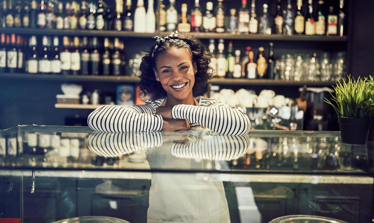 Smiling woman leaning on glass display in modern bistro