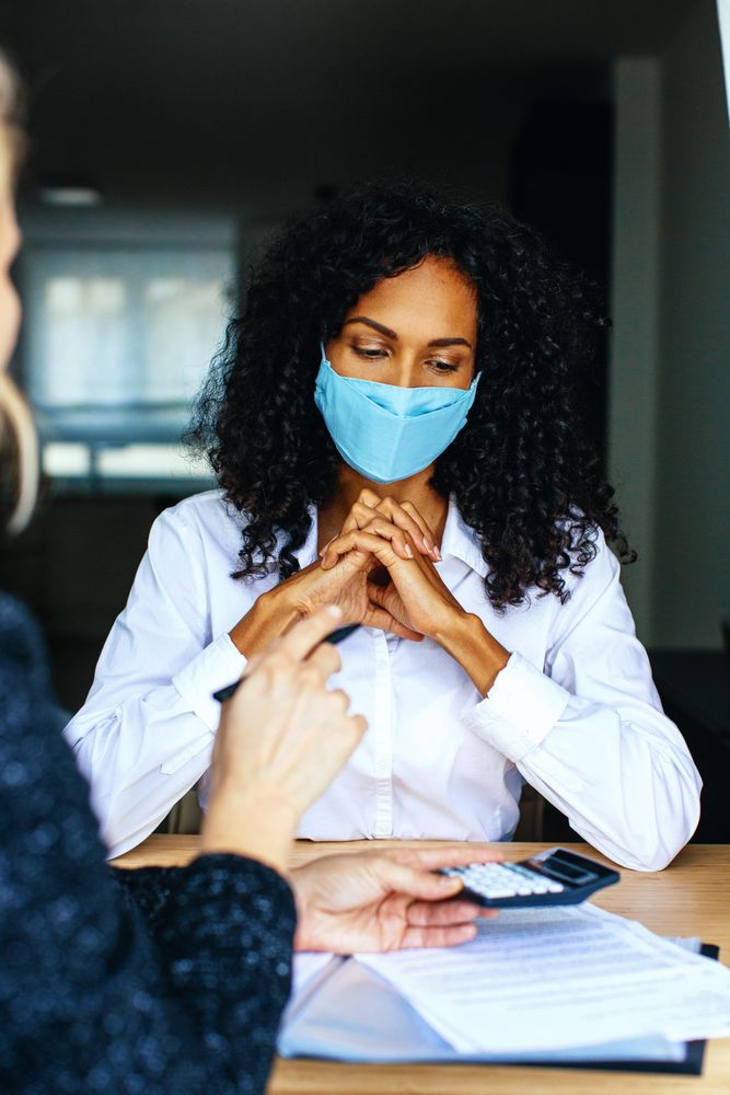 Woman going through calculations with a colleague wearing a facemask