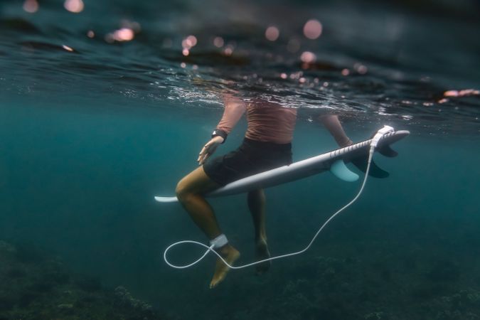 Man sitting on surf board floating in blue water
