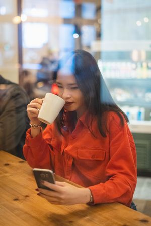 Woman having a cup of coffee using mobile phone
