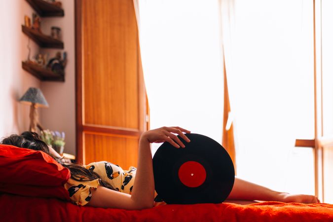Charming woman with vinyl record in bedroom