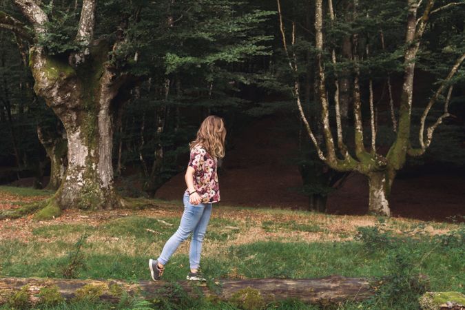 Young woman balancing on log in park