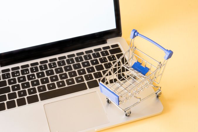 Miniature Shopping Cart on Laptop Depicting Concept of Online Shopping