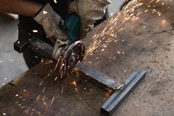 Male worker using electric grinder in workshop