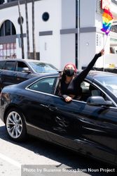 Los Angeles, CA, USA — June 14th, 2020: woman smiling at camera waving rainbow flag from car window 4Ba7e5
