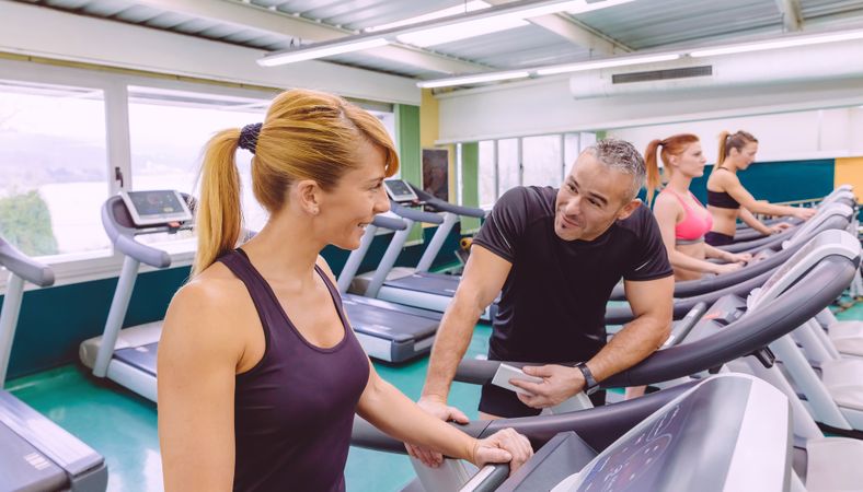 Man and woman chatting on treadmills in gym