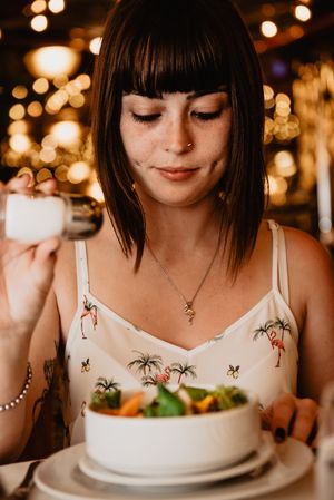 Woman salting salad in restaurant