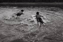 Happy boys swimming with board over water