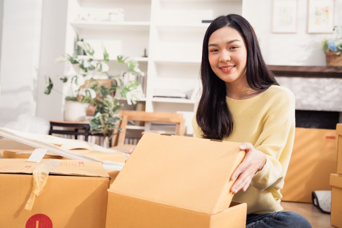 Happy Asian woman with cardboard boxes for moving to the new home