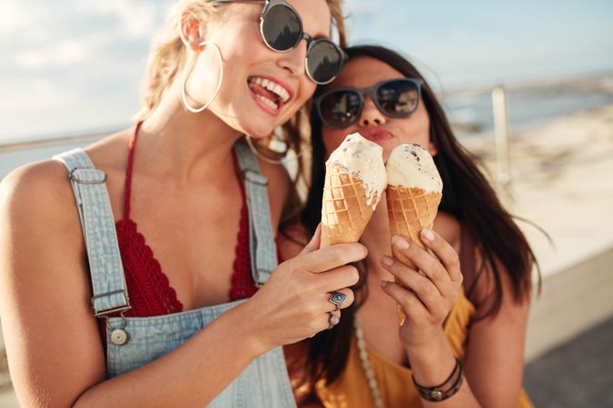 Portrait of two young women standing together eating ice cream