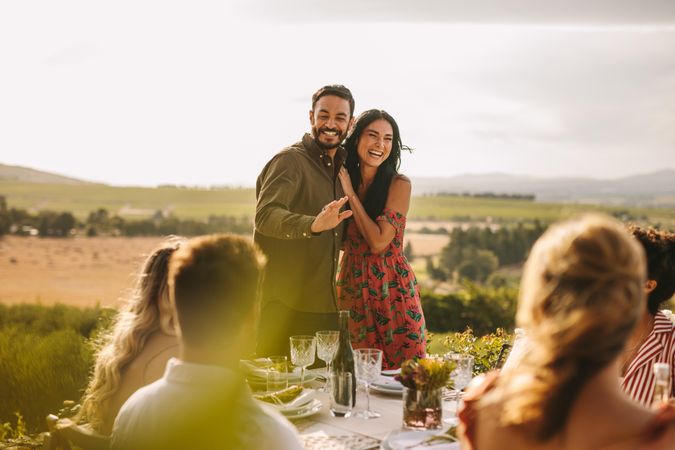 Smiling man and woman making an announcement during a dinner party outdoors